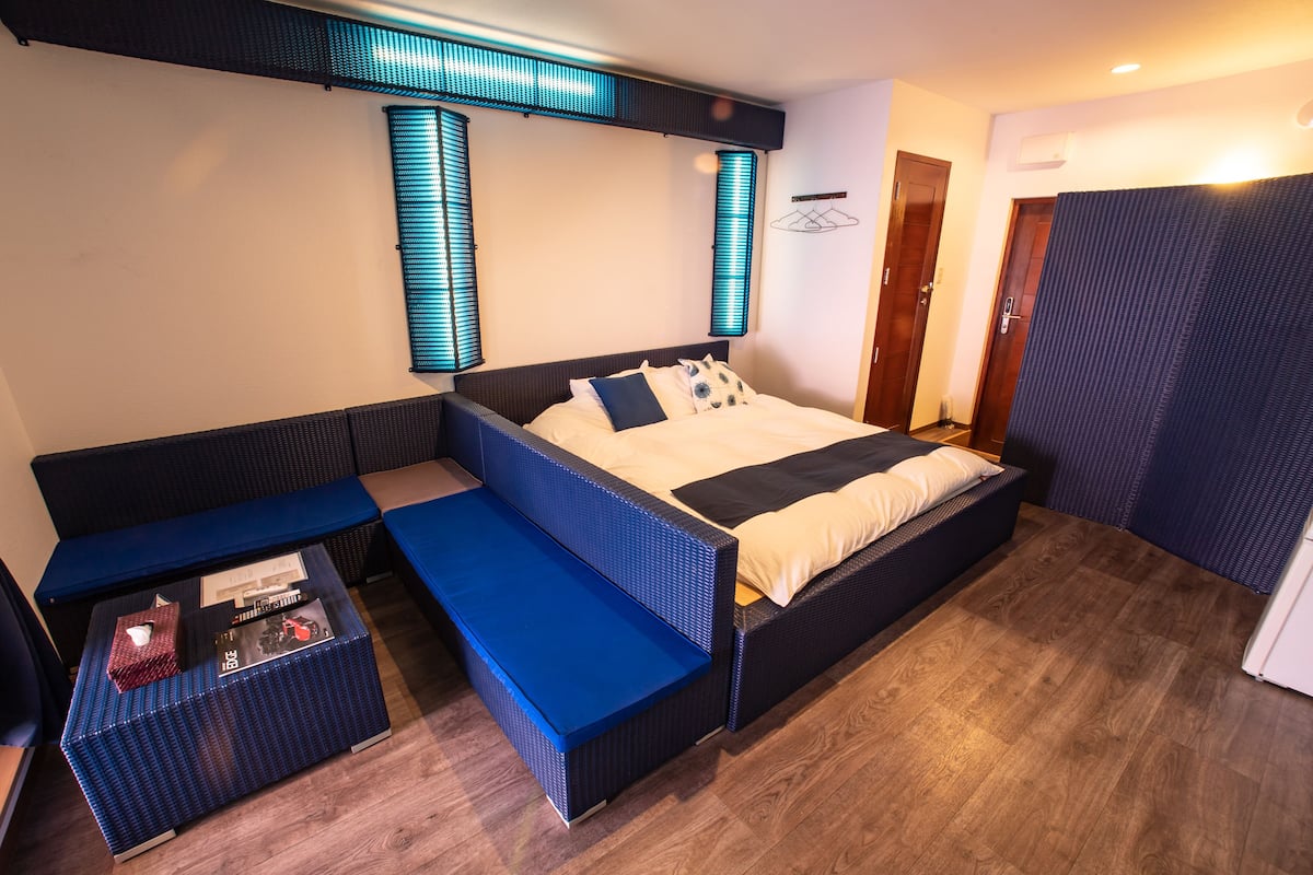 A modern hotel room with a large bed, a seating area, and a small table.