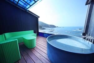 Una terraza de madera con un jacuzzi grande y asientos verdes.
