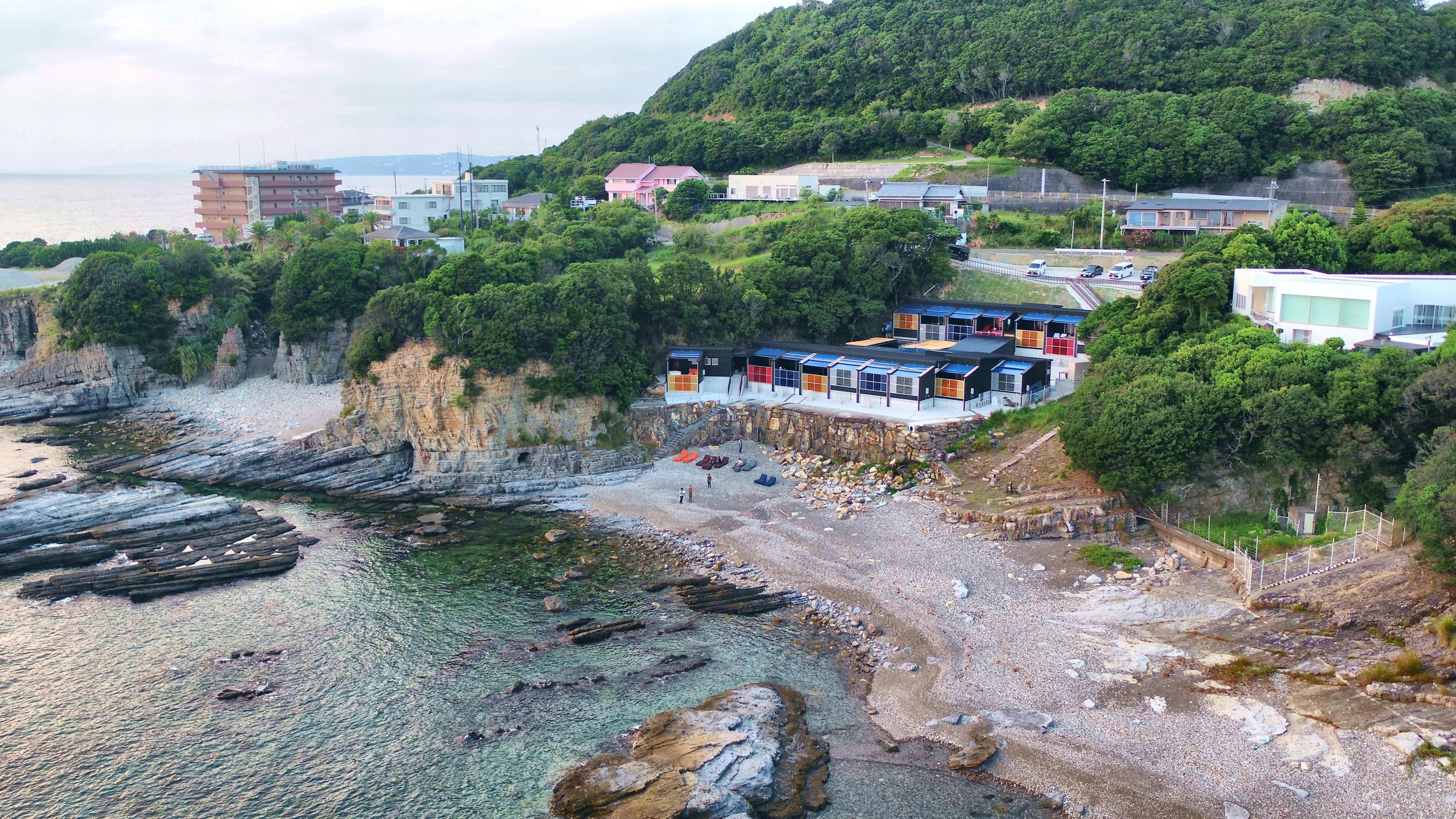 Una zona costiera con spiaggia rocciosa, una scogliera con edifici e vista sul mare.