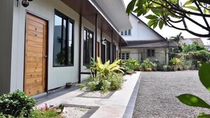 Una casa moderna con puerta de madera, ventanas grandes y camino de entrada de grava.