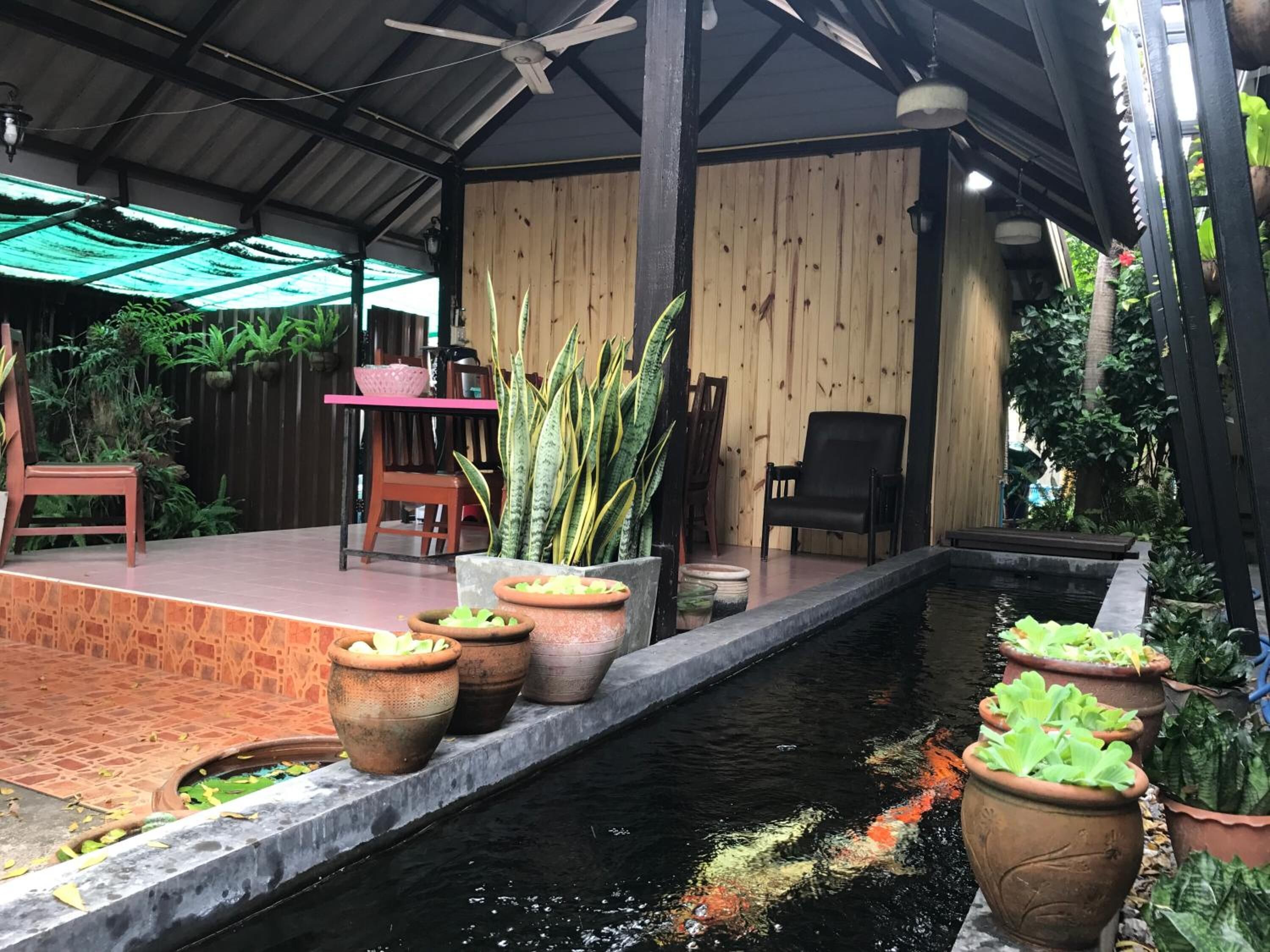 A covered outdoor area with a pool, potted plants, and seating.