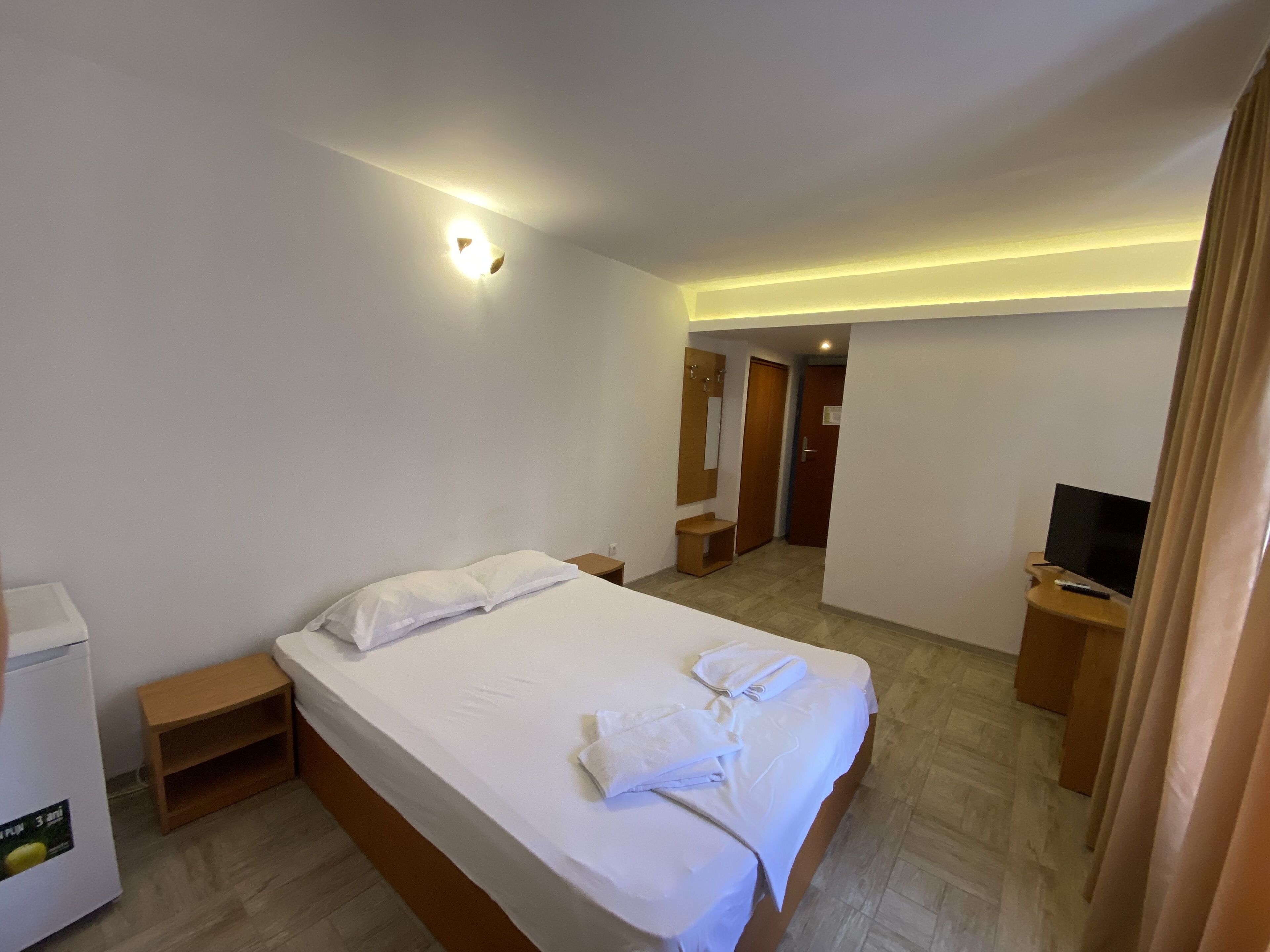 Une chambre d’hôtel avec un lit, des tables de chevet, une télévision et un miroir.