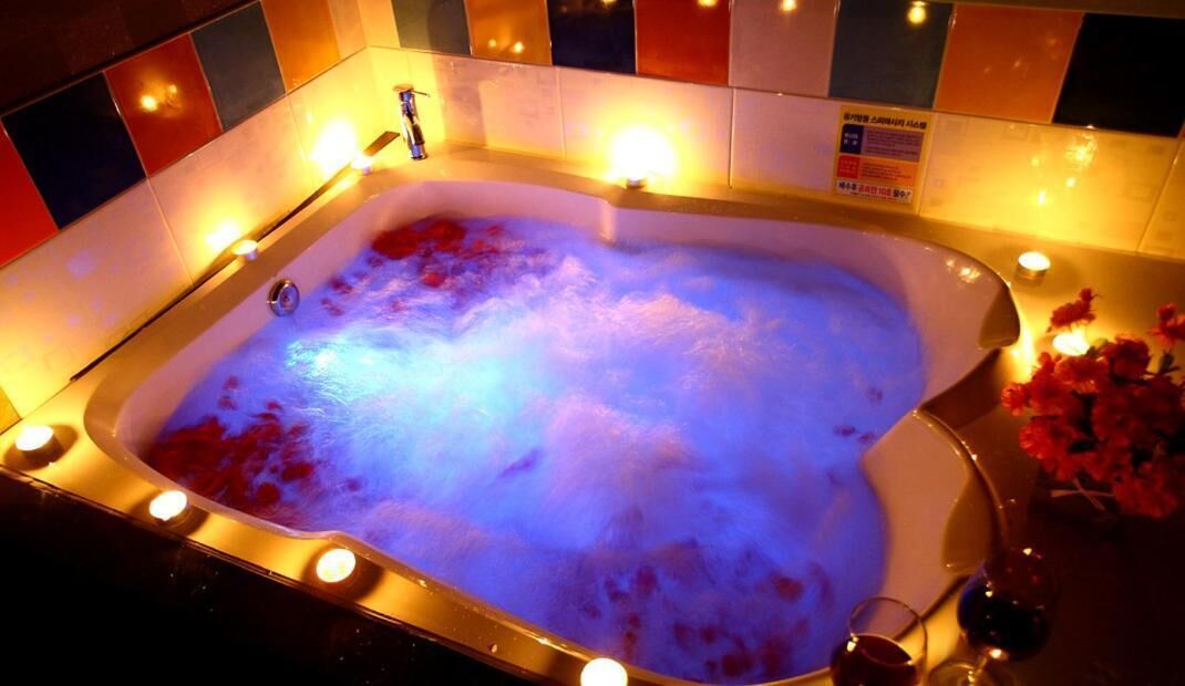 A hot tub with a tiled surround and a sign on the wall.
