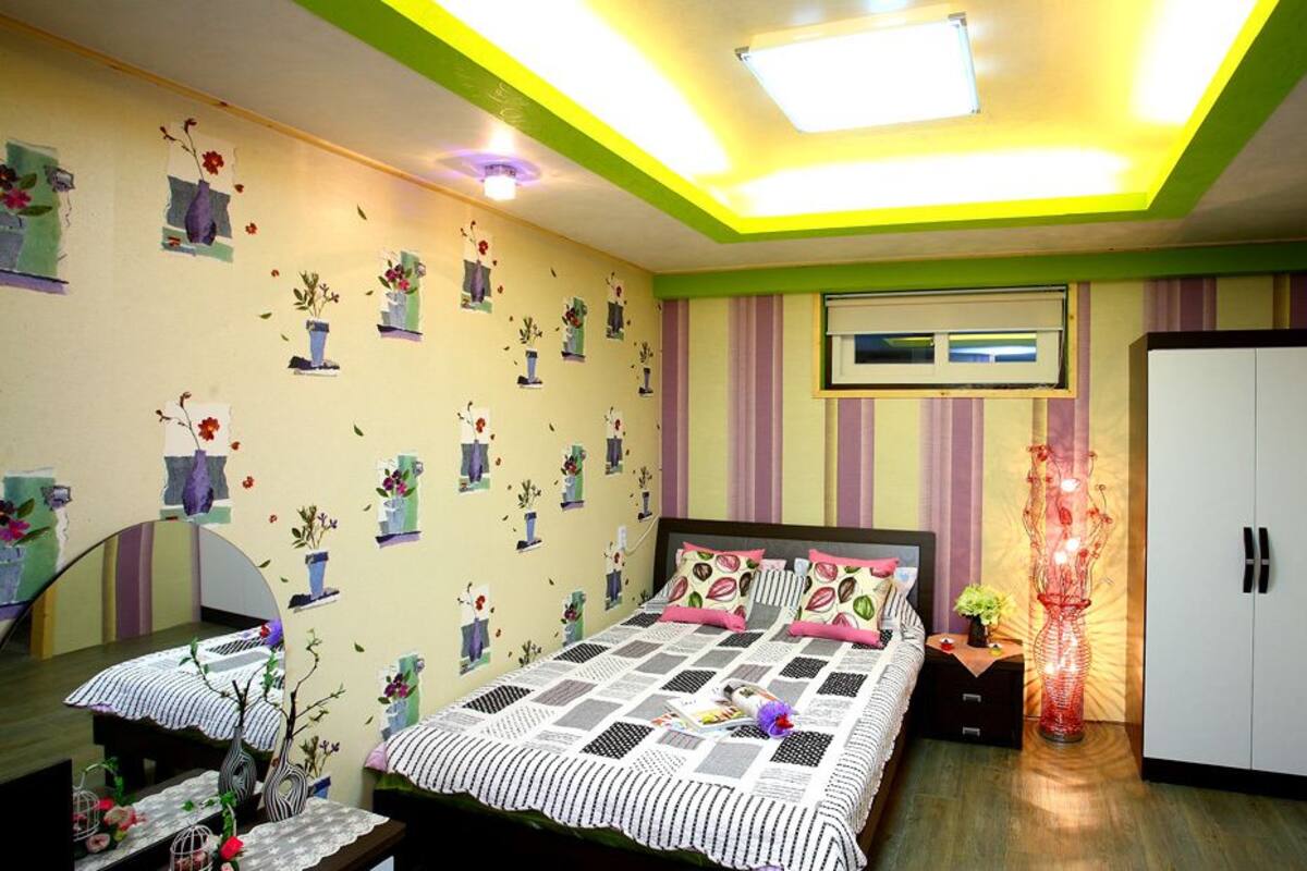 A bedroom with a bed, bedside tables, a wardrobe, and a wall-mounted TV.