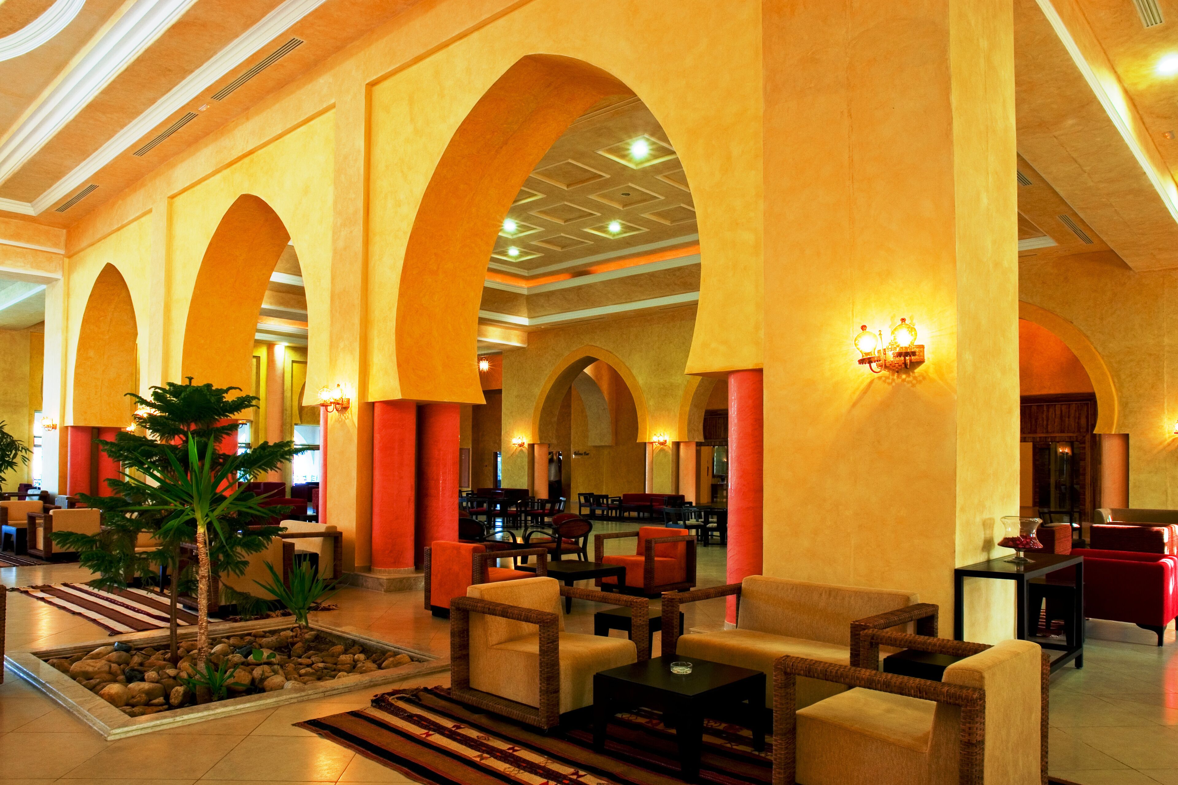 A spacious lobby with high ceilings, arched columns, and a central seating area with sofas and tables.