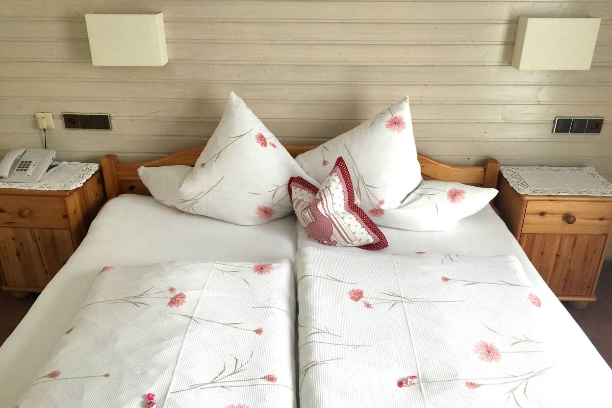 A double bed with floral bedding, two nightstands with lamps, and a telephone on the left nightstand.