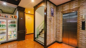 Un vestíbulo con una máquina expendedora, una escalera y un ascensor.