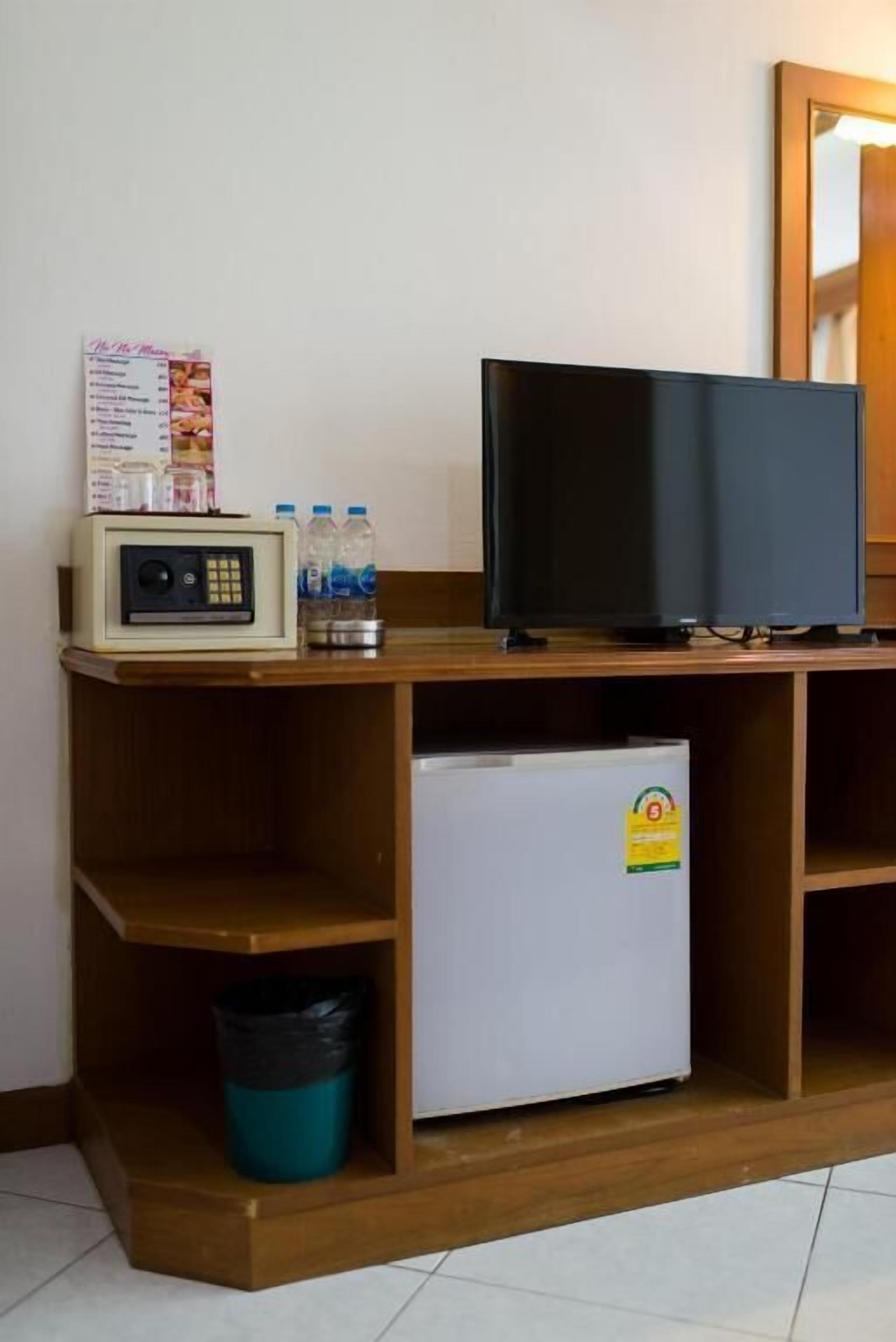 A small kitchenette with a microwave, a refrigerator, and a television on a wooden shelf.
