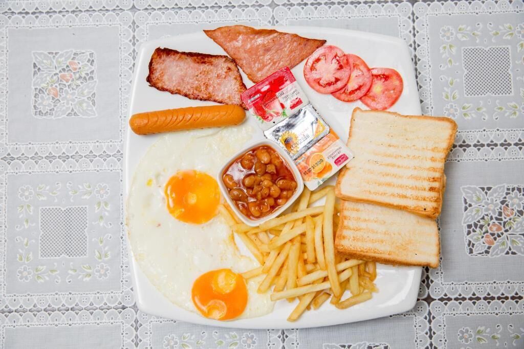 Une assiette composée d’œufs, de bacon, de pain grillé, de tomates, de haricots et de frites.
