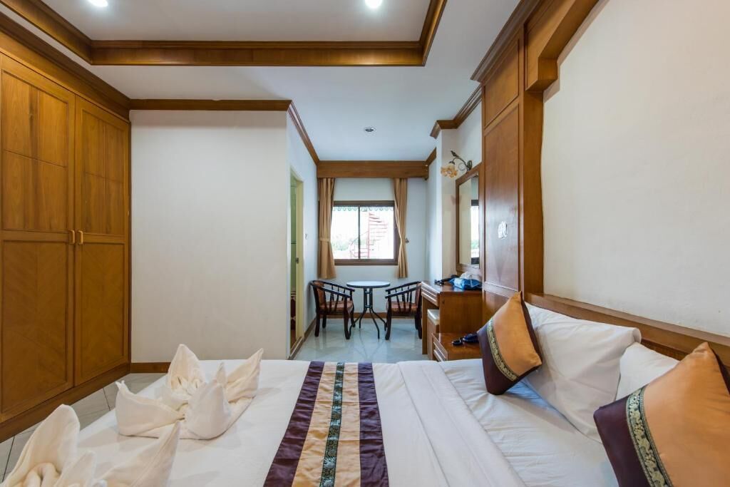 A hotel room with a large bed, a desk, and a chair.