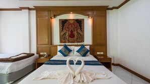 Una habitación de hotel con una cama grande, dos almohadas, una mesita de noche y un tapiz decorativo en la pared.