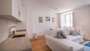 A modern living room with a white sofa, a small table, and a window with natural light. - Alfama Premium by Homing (Lisbon)