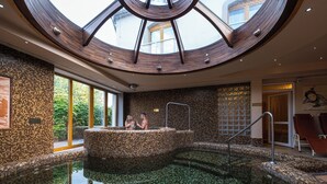 Un área de spa con un jacuzzi circular, una pared de piedra y un tragaluz.