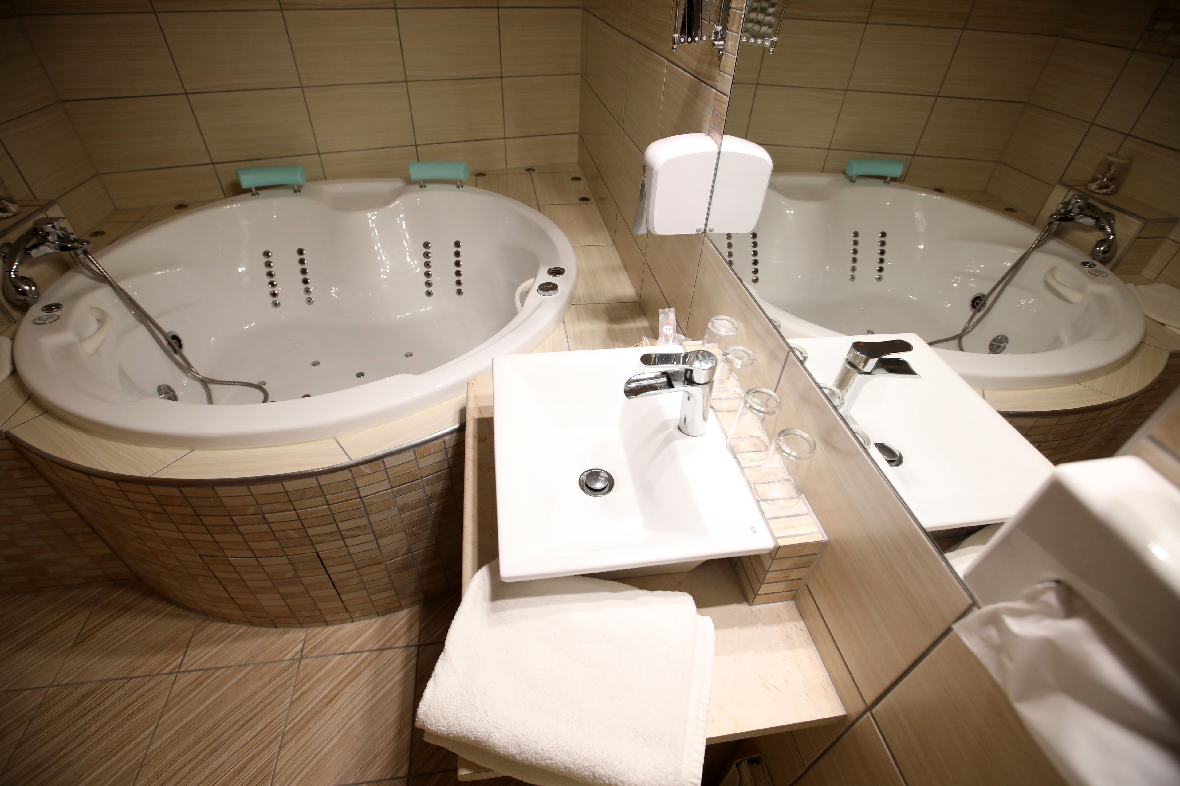 Un baño con dos tinas separadas, un lavabo y un espejo.