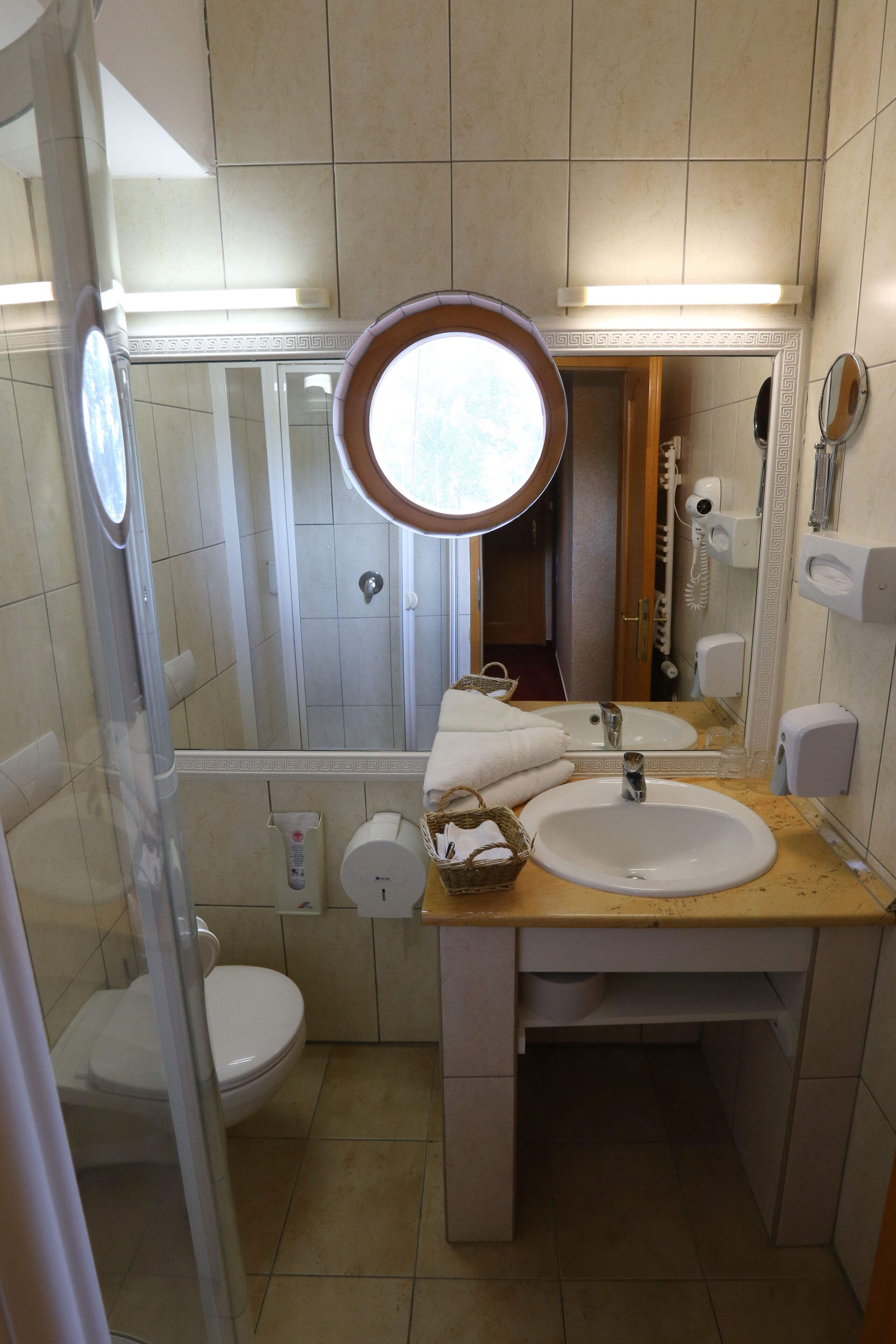 Un baño con lavamanos, espejo, inodoro y ducha.