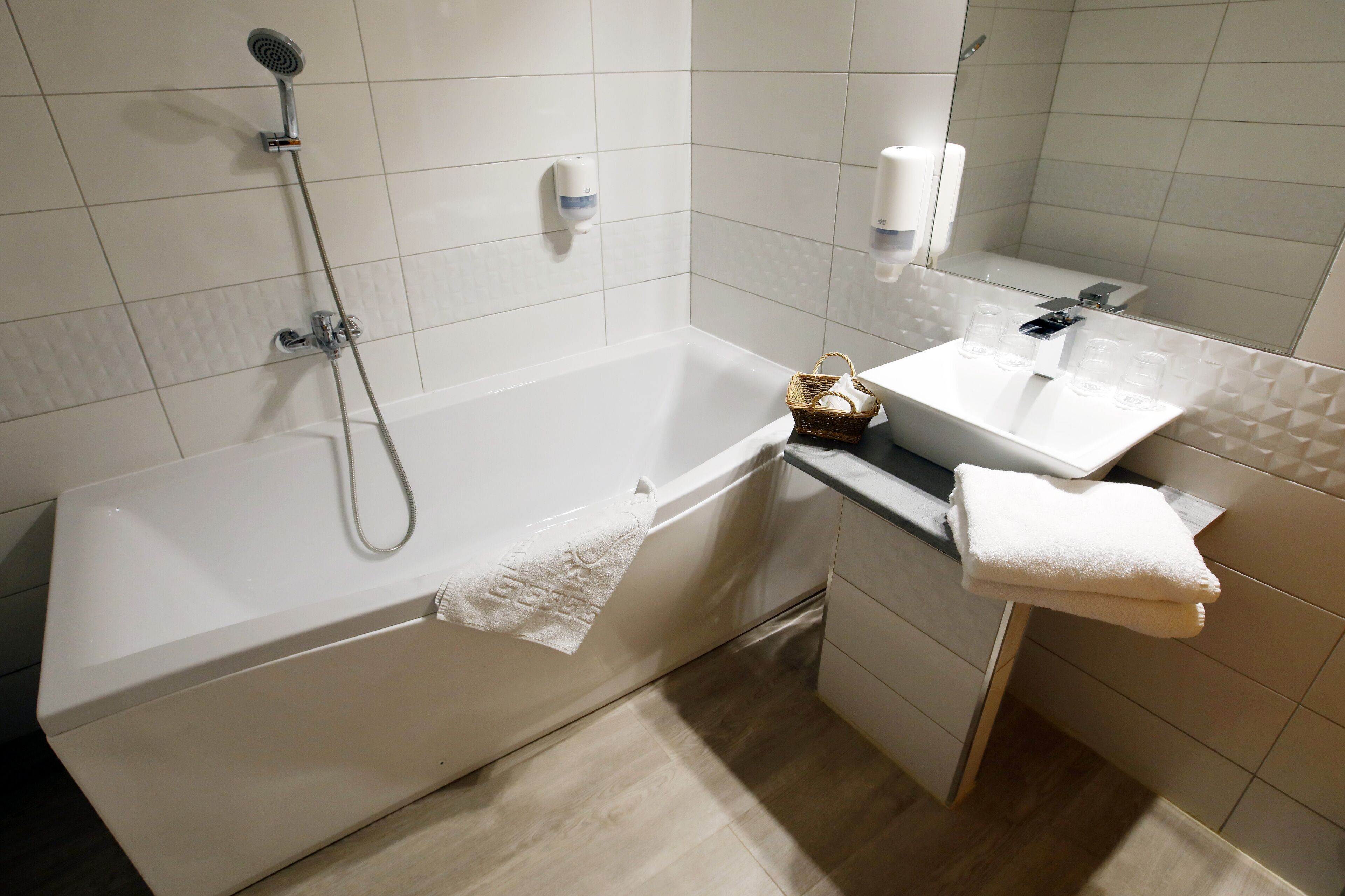 Ein modernes Badezimmer mit Badewanne, Dusche, Waschbecken und Spiegel.