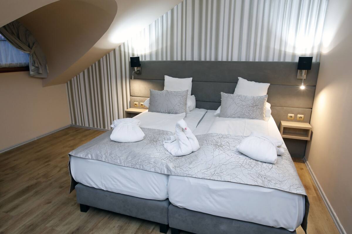A spacious bedroom with a large bed, two bedside tables, and a modern headboard.