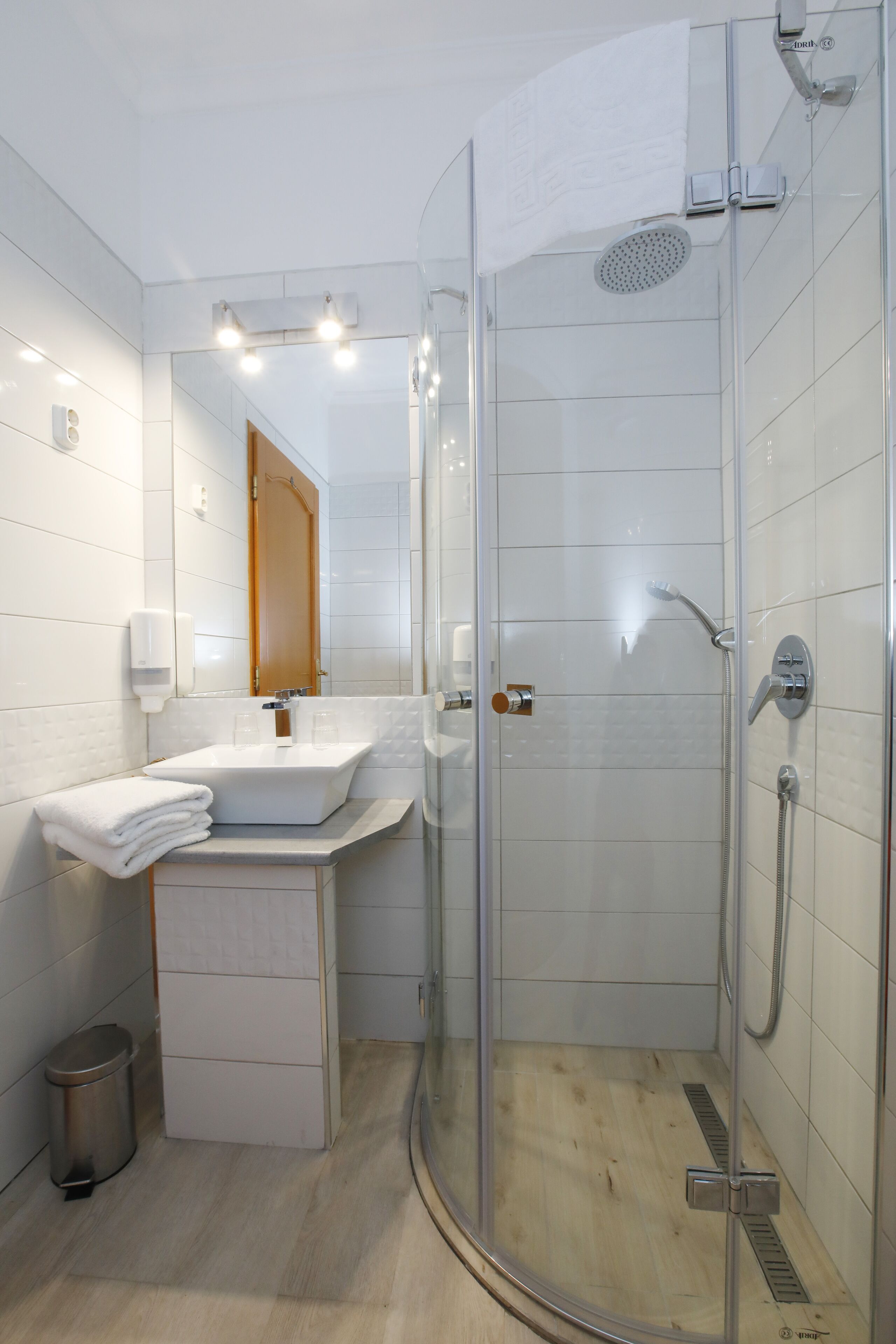 Un baño moderno con cabina de ducha de vidrio, un lavabo blanco y un espejo encima.