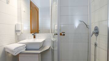 Un baño moderno con cabina de ducha de vidrio, un lavabo blanco y un espejo encima.