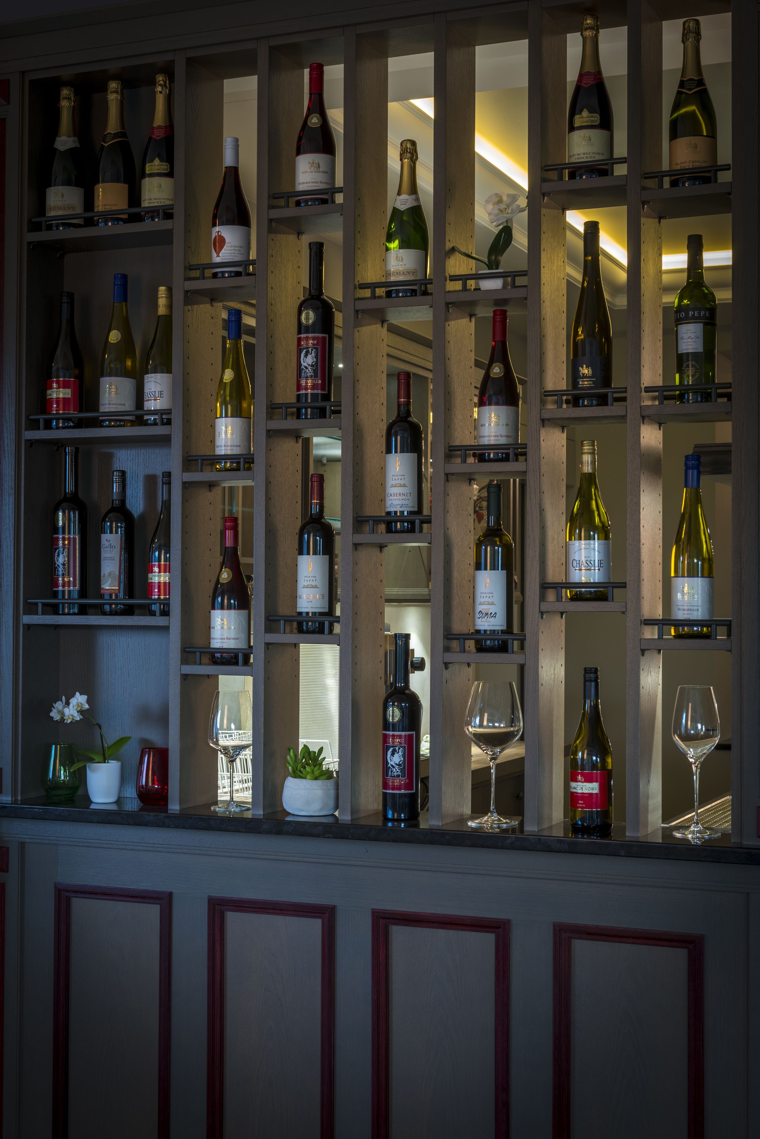 A wine rack with various bottles and glasses.