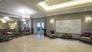 A spacious lobby with a chandelier, seating area, and a large wall painting. - Park Hotel & Spa Katharina (Badenweiler)