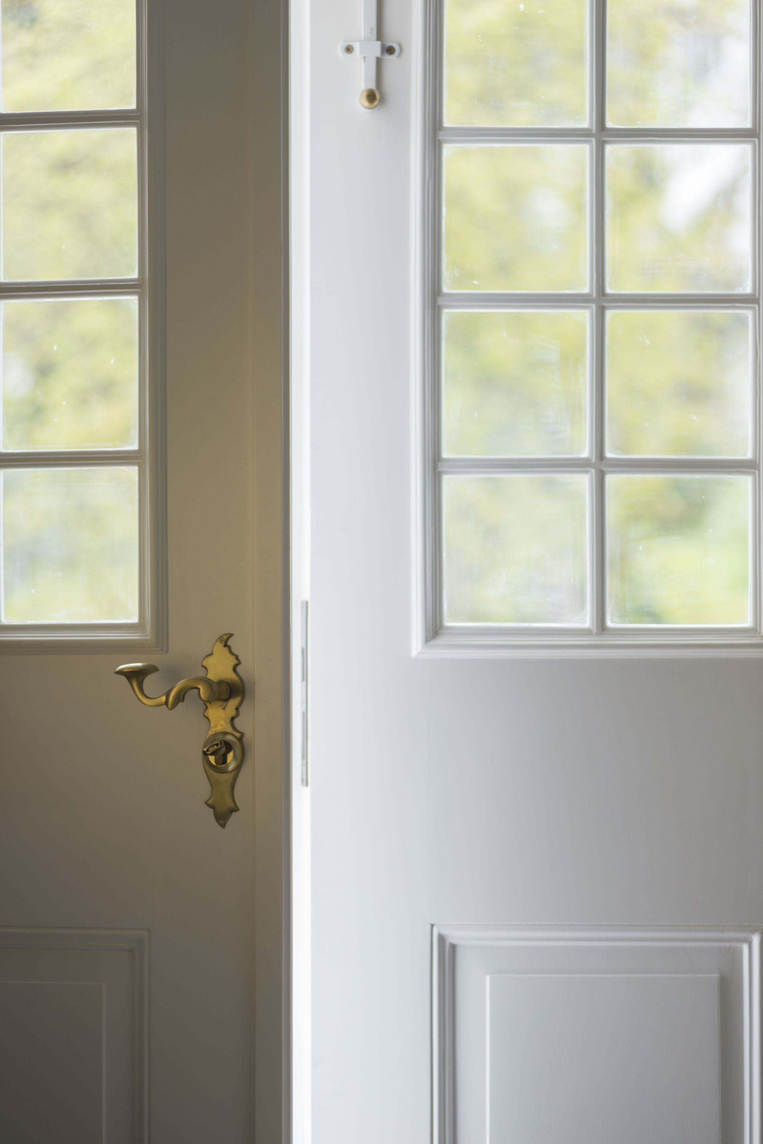 Una puerta blanca con pomo de latón y una ventana con diseño de cuadrícula.