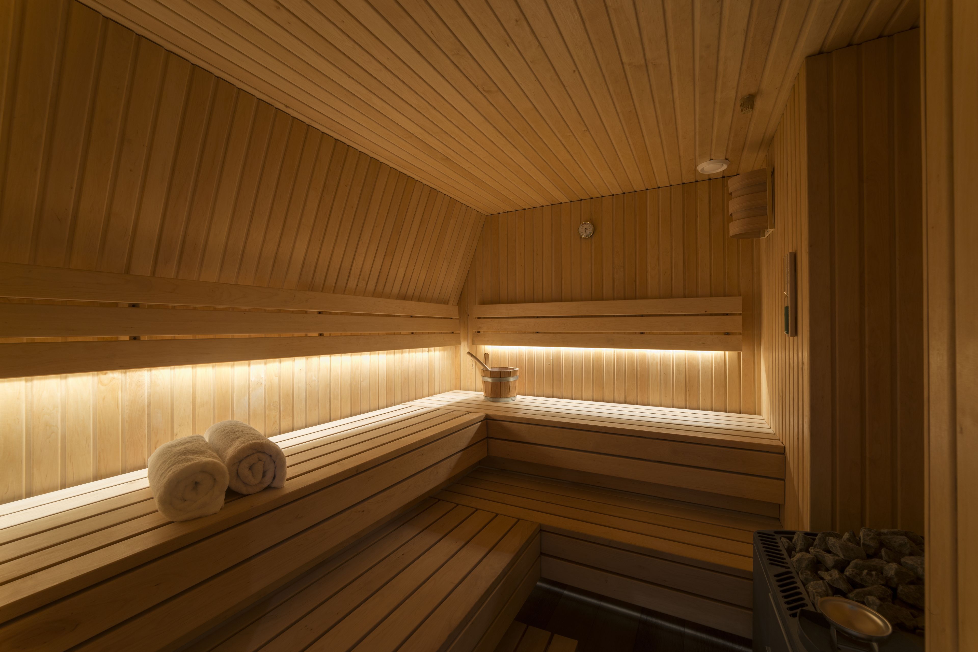 Eine Sauna mit Holzbänken, einem Eimer und einer Heizung.