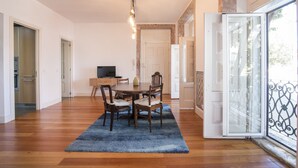 Un vaste espace dédié à la salle à manger, avec une table et des chaises en bois, un tapis bleu et un lustre moderne.