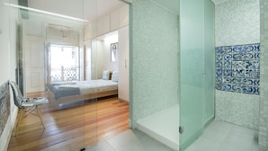 Une chambre moderne avec une cloison en verre, un lit et un espace douche.