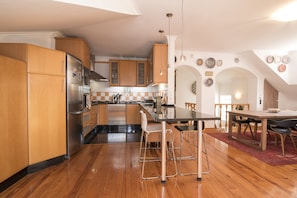 A modern kitchen with wooden cabinets, stainless steel appliances, and a dining area with a table and chairs.