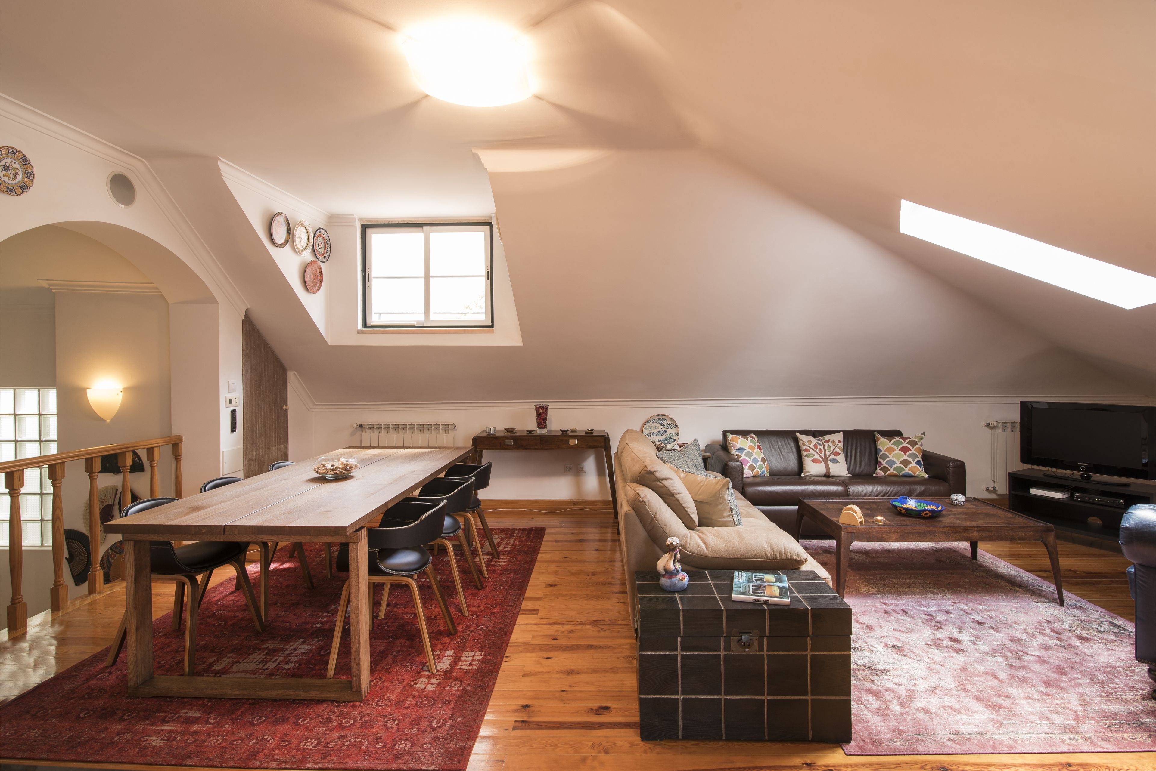 A spacious loft with a dining area, a sofa, a TV, and a staircase.