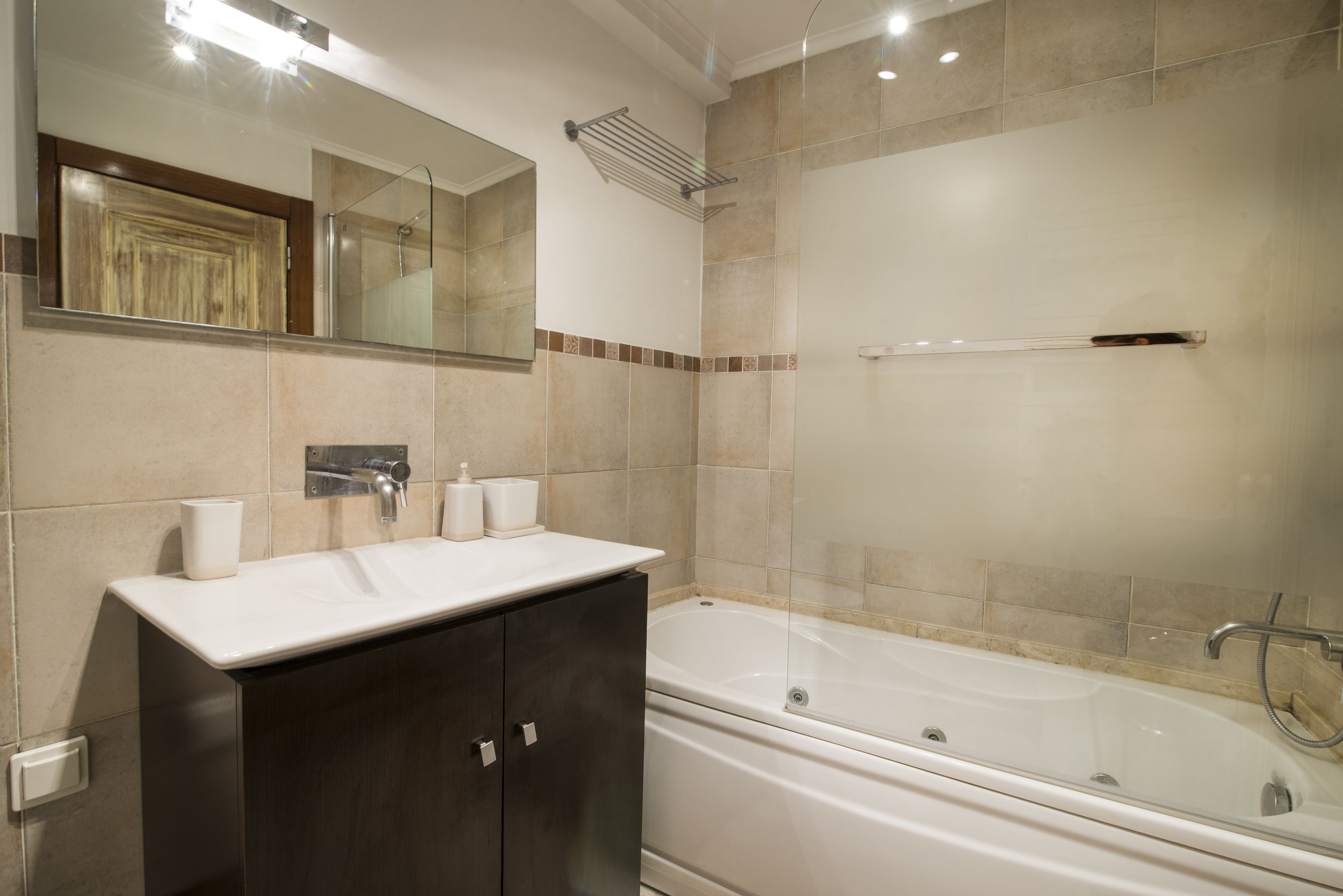 Un bagno moderno con una vasca, un mobile toilette con specchio e un porta asciugamani.