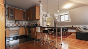 Una cocina moderna con armarios de madera, una encimera negra y una zona de comedor con mesa y sillas.