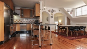 Una cocina moderna con armarios de madera, electrodomésticos de acero inoxidable y un comedor con una mesa grande y sillas.