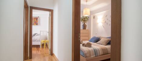 A bedroom with a wooden bed, a bedside table, a lamp, and a wall-mounted light fixture.
