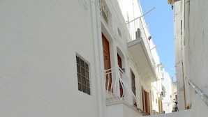 A narrow, white-walled alley with stone steps leading to a building with balconies. - Casa Baldassarre (Ostuni)