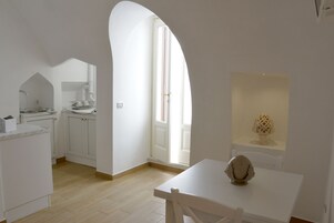 A kitchen with white cabinets, a dining table, and a window with natural light.