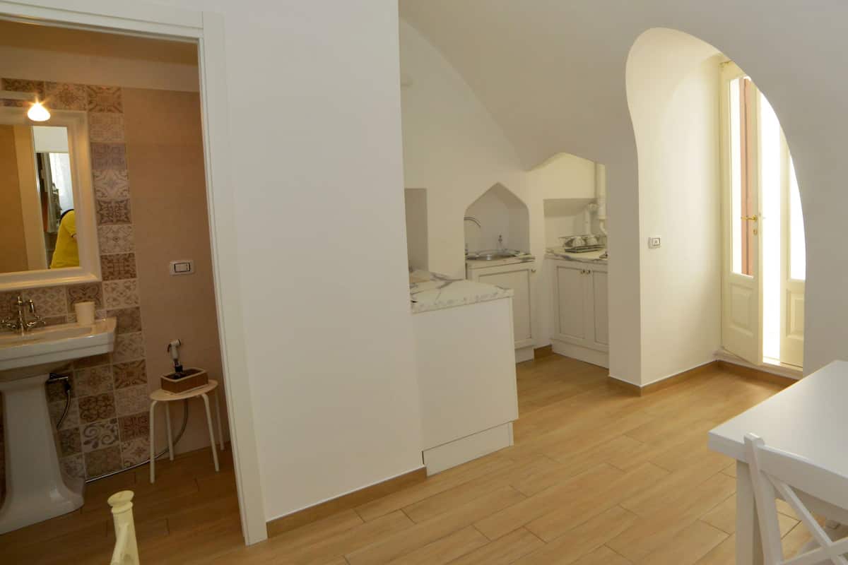 A modern kitchen with white cabinetry, a wooden floor, and a dining area with a white table and chairs.