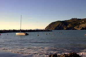 A calm bay with a sailboat anchored near rocky shores, surrounded by buoys. - Affittacamere LevantoMare (Levanto)