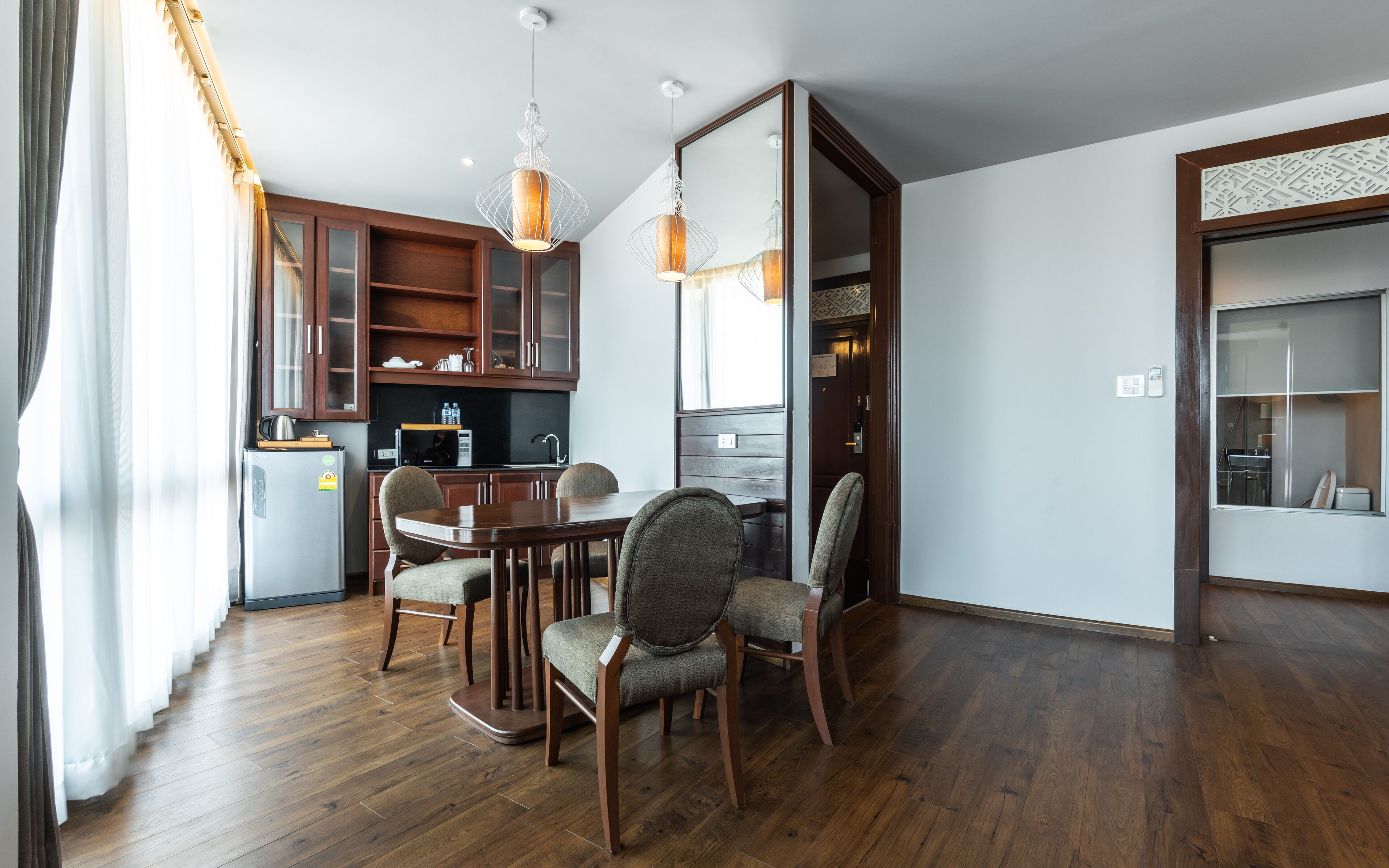 A modern kitchen with wooden cabinets, a dining table with chairs, and pendant lighting.