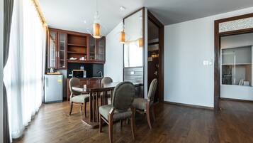 A modern kitchen with wooden cabinets, a dining table with chairs, and pendant lighting.