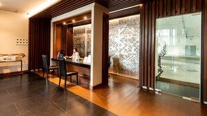 Una zona de recepción con un mostrador de madera, sillas y una puerta de cristal que da al exterior.