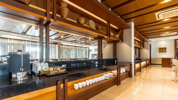 Zona de buffet con una larga barra, varias estaciones de servicio y una variedad de platos.