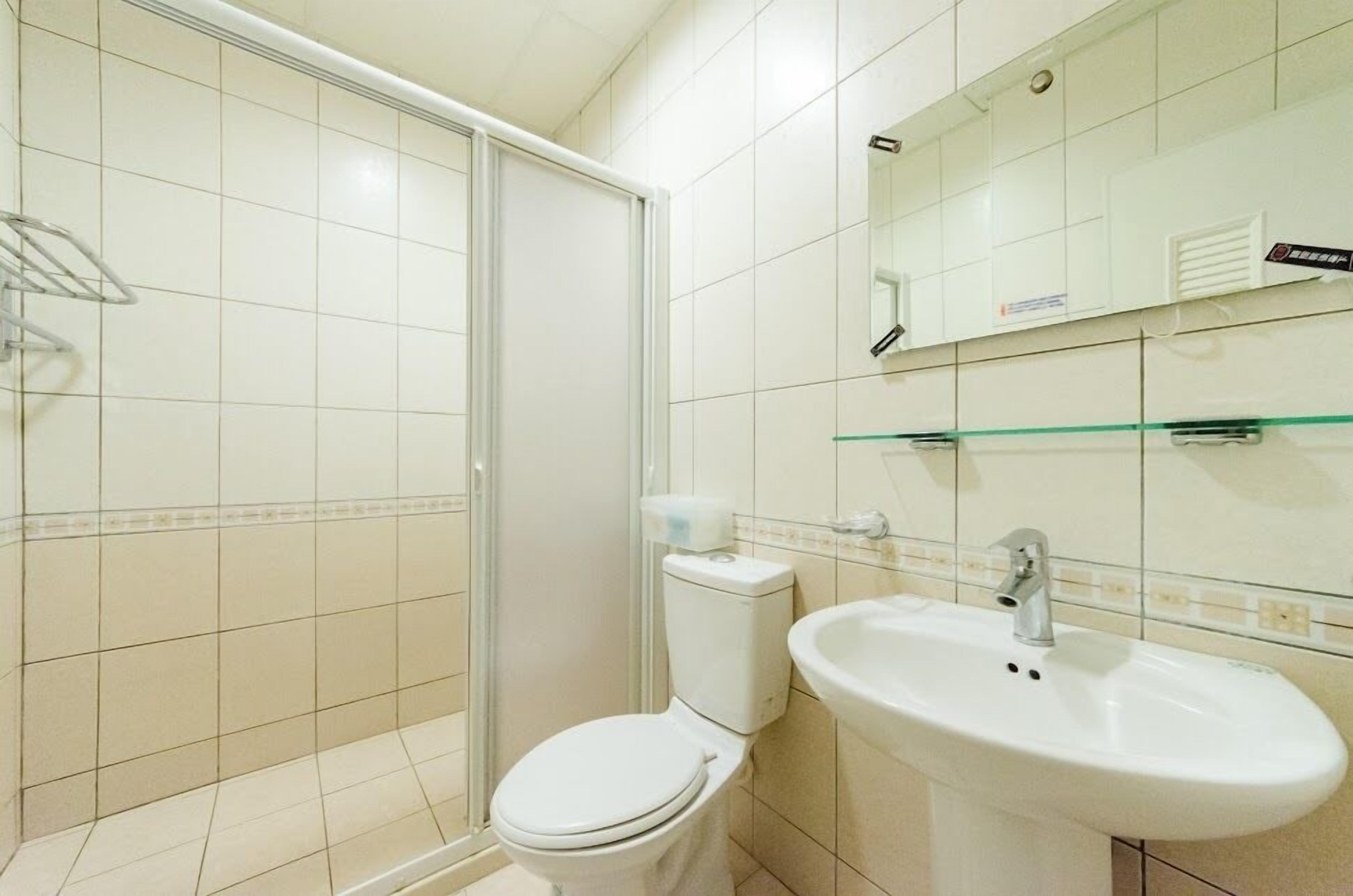 A bathroom with a toilet, sink, and glass shower enclosure.