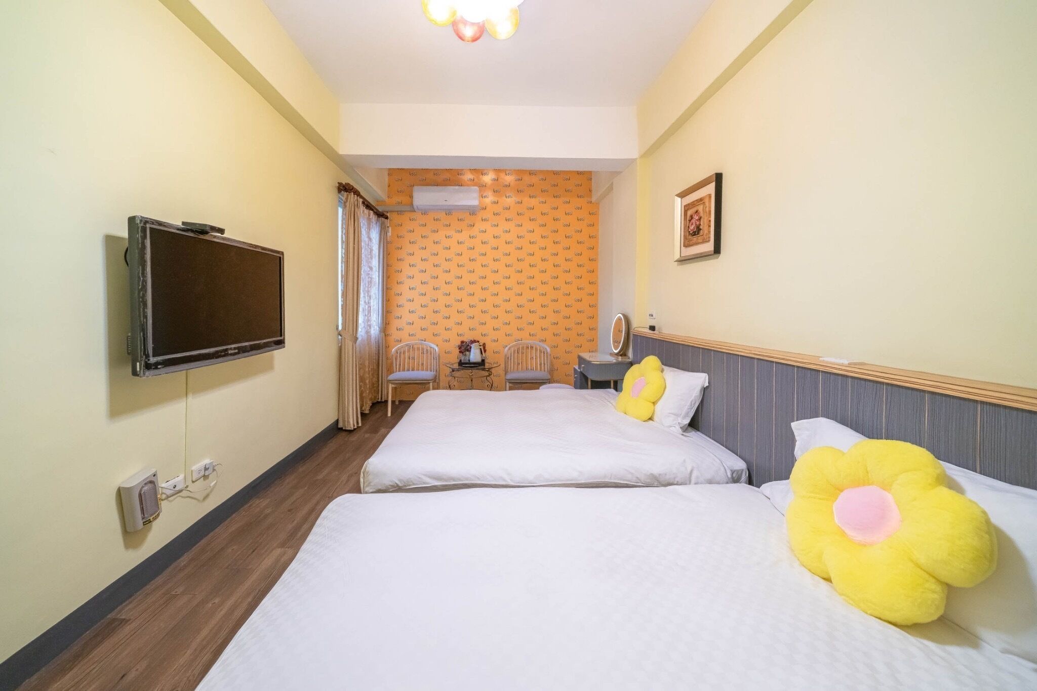 A hotel room with two beds, a television, a small table, and a chair.