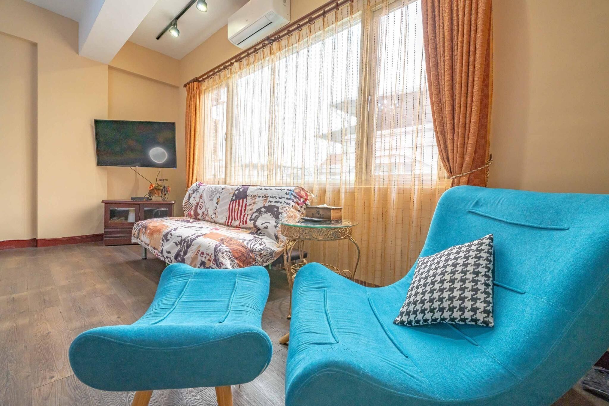 Una habitación con un sofá, una pequeña mesa y un televisor montado en la pared.