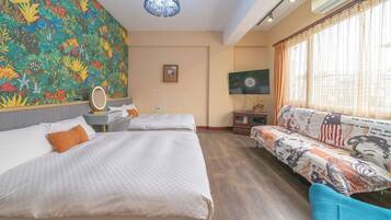 A hotel room with a large bed, a sofa, a TV, and a colorful floral wall.
