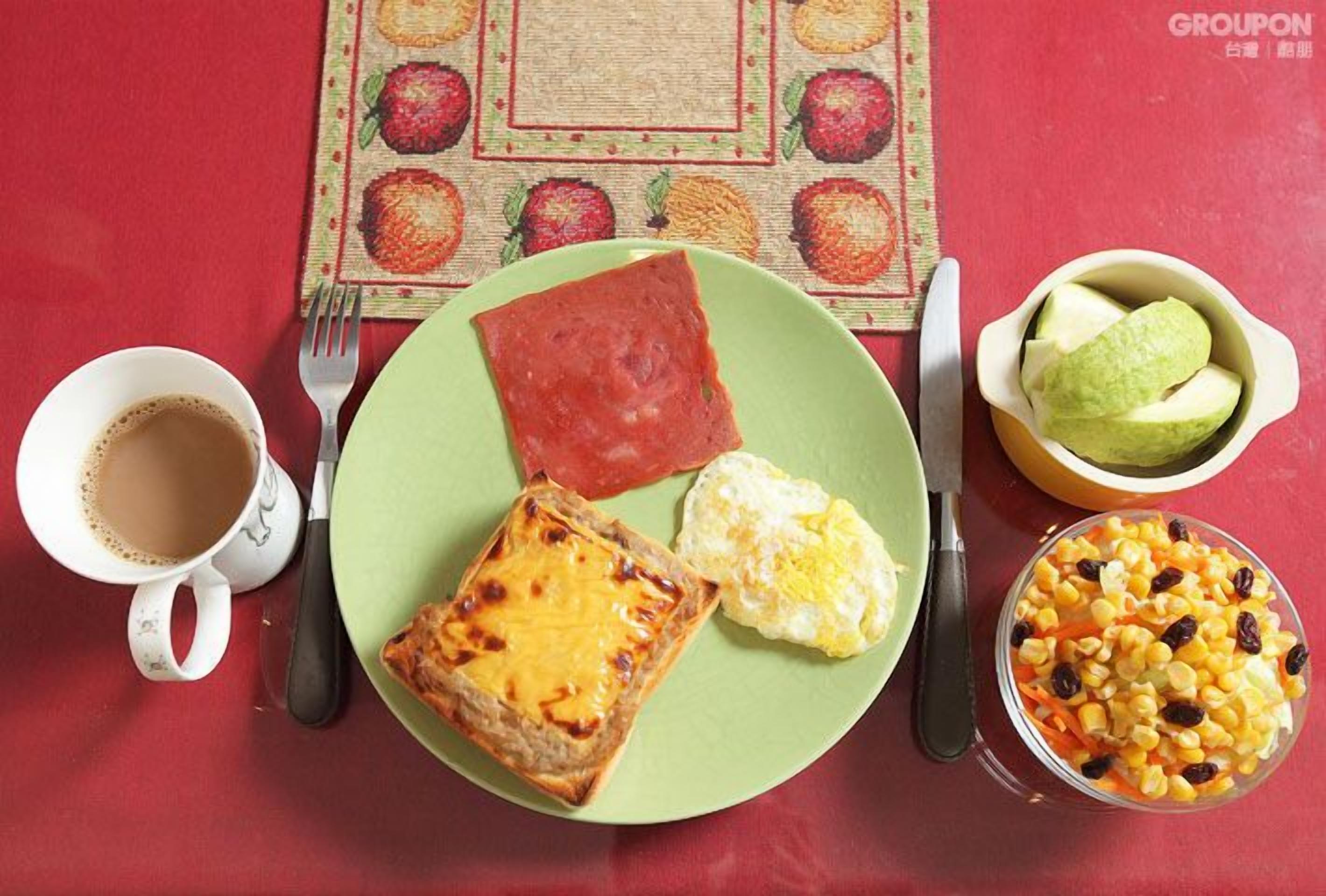 A meal with toast, eggs, and a fruit bowl on a table with a red tablecloth.