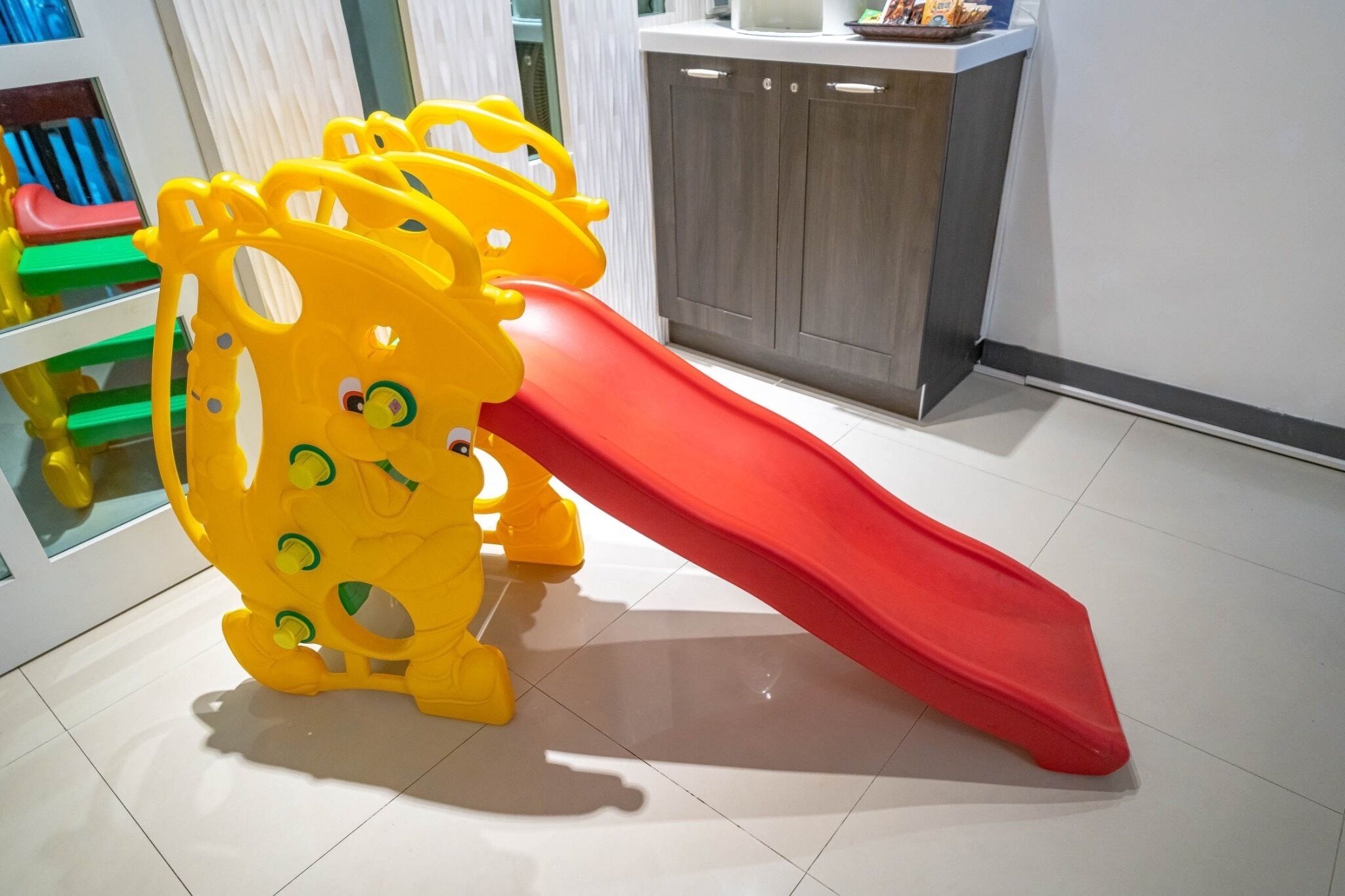 A children's play area with a yellow play structure and a red slide.