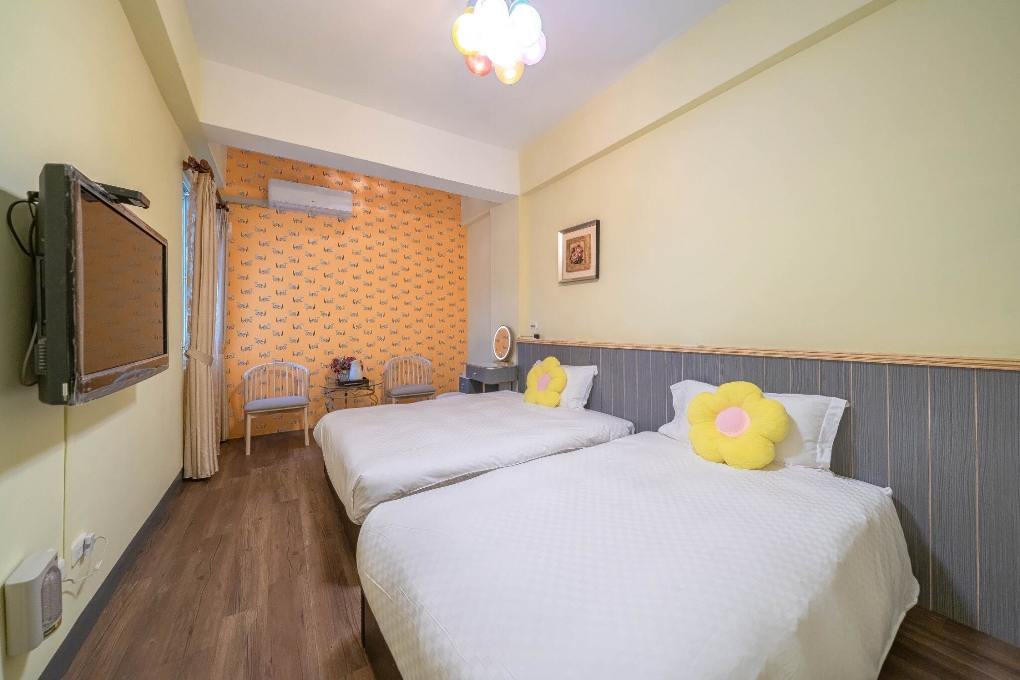 Ett hotellrum med två sängar, ett skrivbord, en stol, en luftkonditioneringsanläggning och en tv.